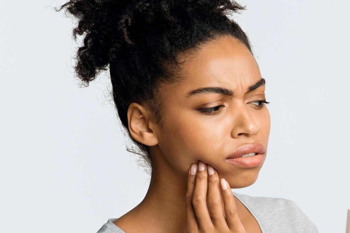 Woman holding her jaw in discomfort, illustrating jaw pain and clicking concerns.