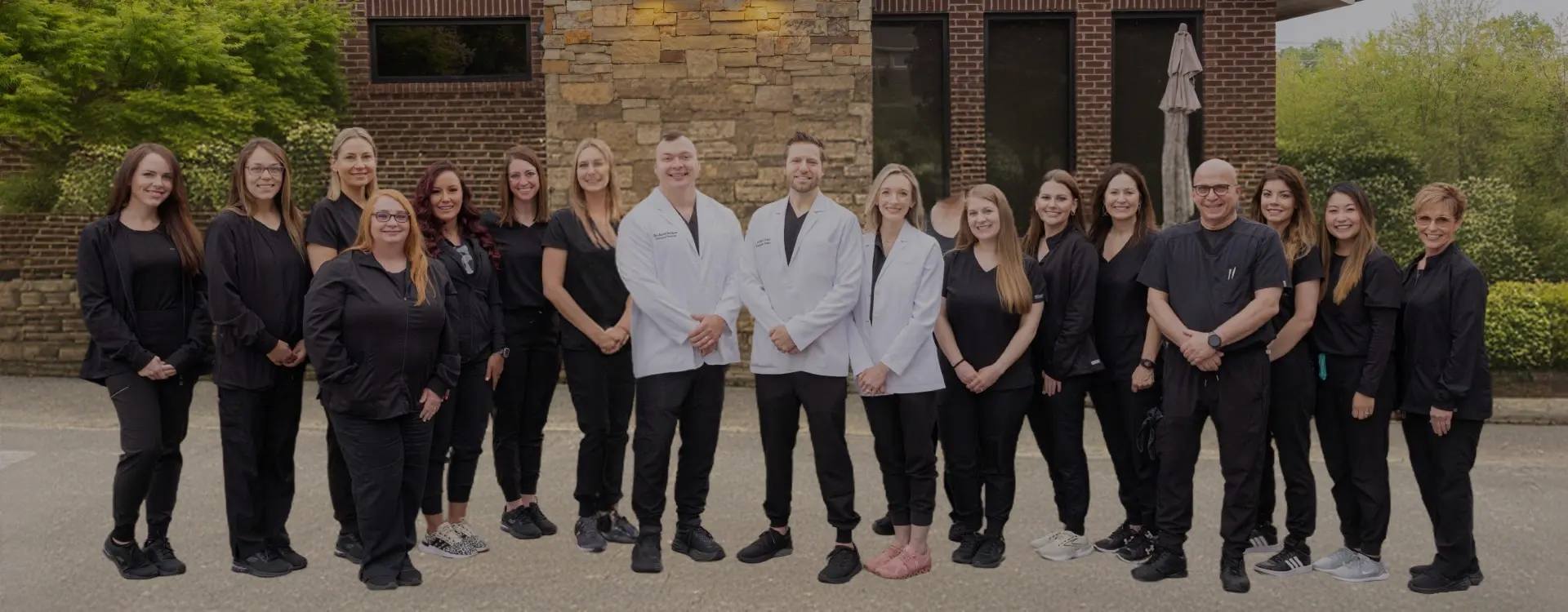 Dental practice team of dentists and staff members posing together outside brick building in Knoxville.